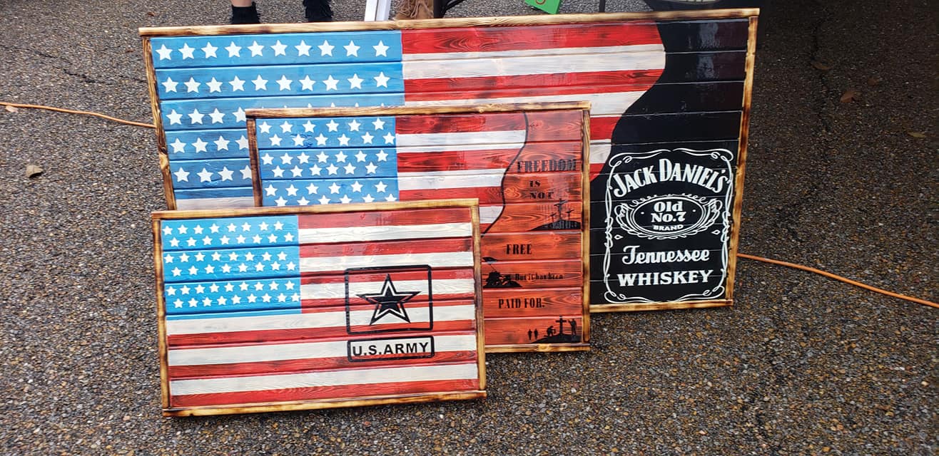 Three wooden American flags next to a Jack Daniels sign.